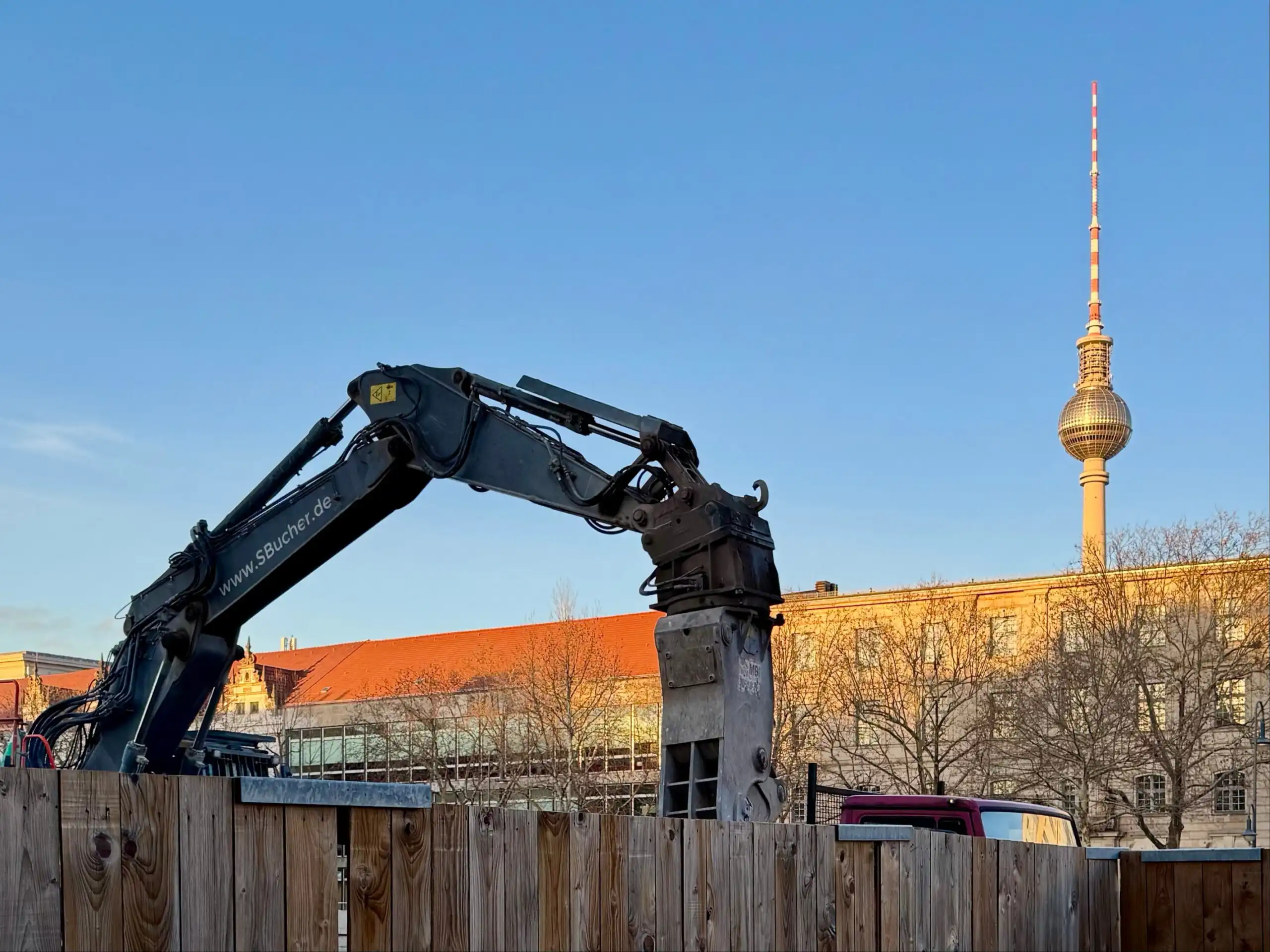 Im Forderung ist ein Baggerkran von einer Baustelle zu sehen, im Hintergrund der Berliner Fernsehturm.