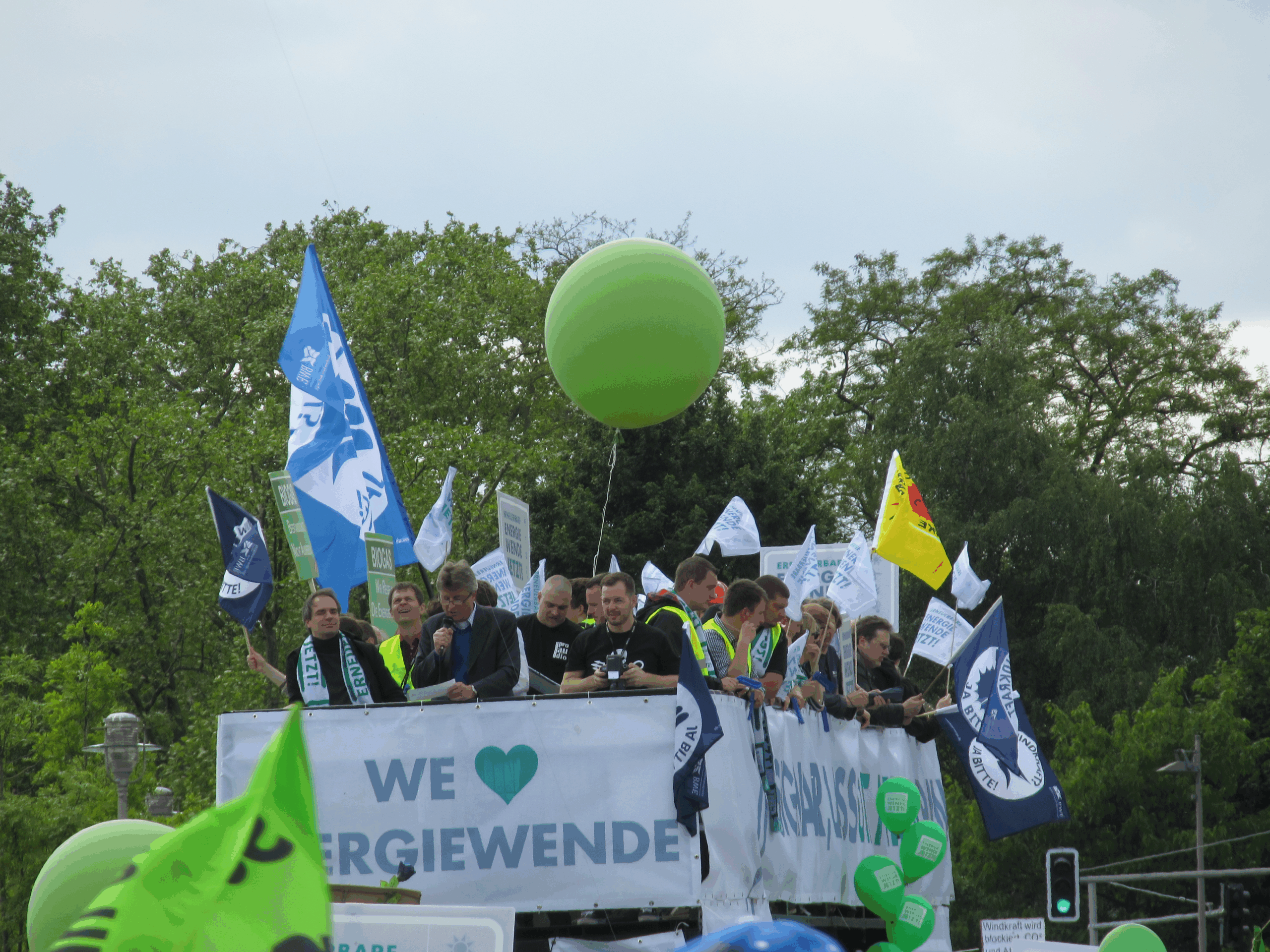Demo für die Energiewende. Menschen auf einem Wagen mit Plakaten und Fahnen.