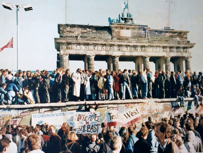 Menschen stehen auf der Berliner Mauer vor dem brandenburger Tor 1989
