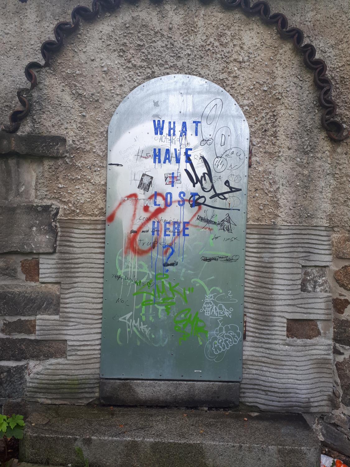 Metalltür in Steinwand mit der Aufschrift "What have we lost here?"