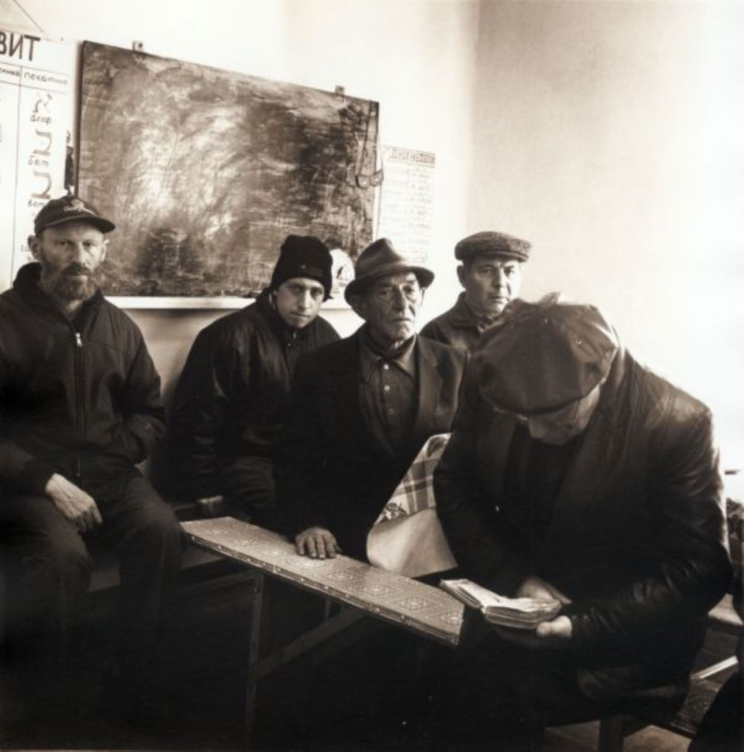 F&uuml;nf M&auml;nner sitzen in einer Synagoge. Vier von ihnen schauen in die Kamera einer schaut in ein Heft.