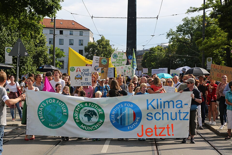 Demonstrierende der Fridays-for-Future-Bewegung laufen in München über eine Straße. Sie wehen Fahnen und tragen ein großes Banner mit der Aufschrift "Klimaschutz jetzt!"