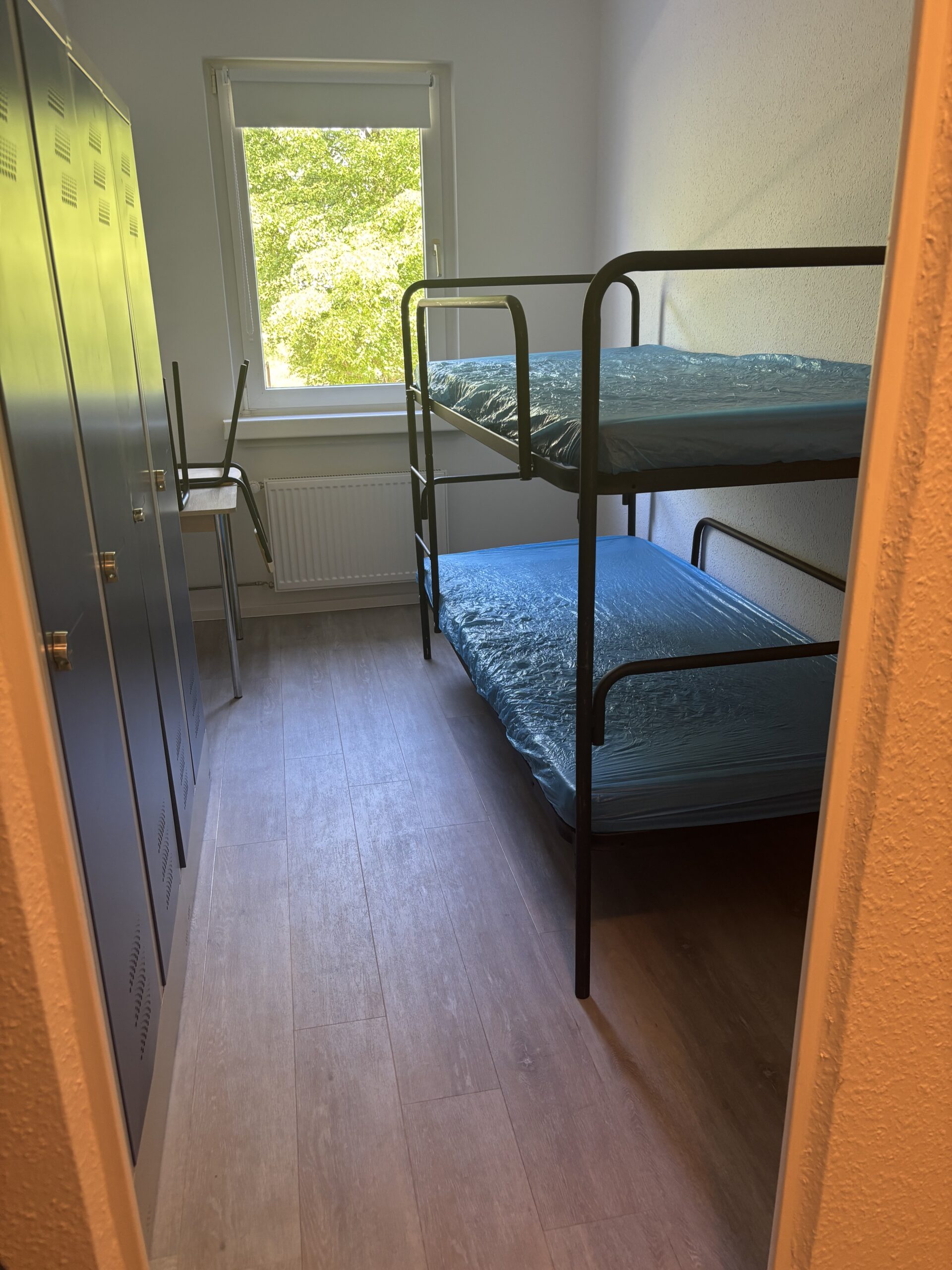 Einrichtung in einer typischen Plattenbauwohnung: Ein Doppelstockbett gegen&uuml;ber eines Schranks, daneben ein Tisch mit Stuhl. Das Zimmer ist klein, die Einrichtung spartanisch.